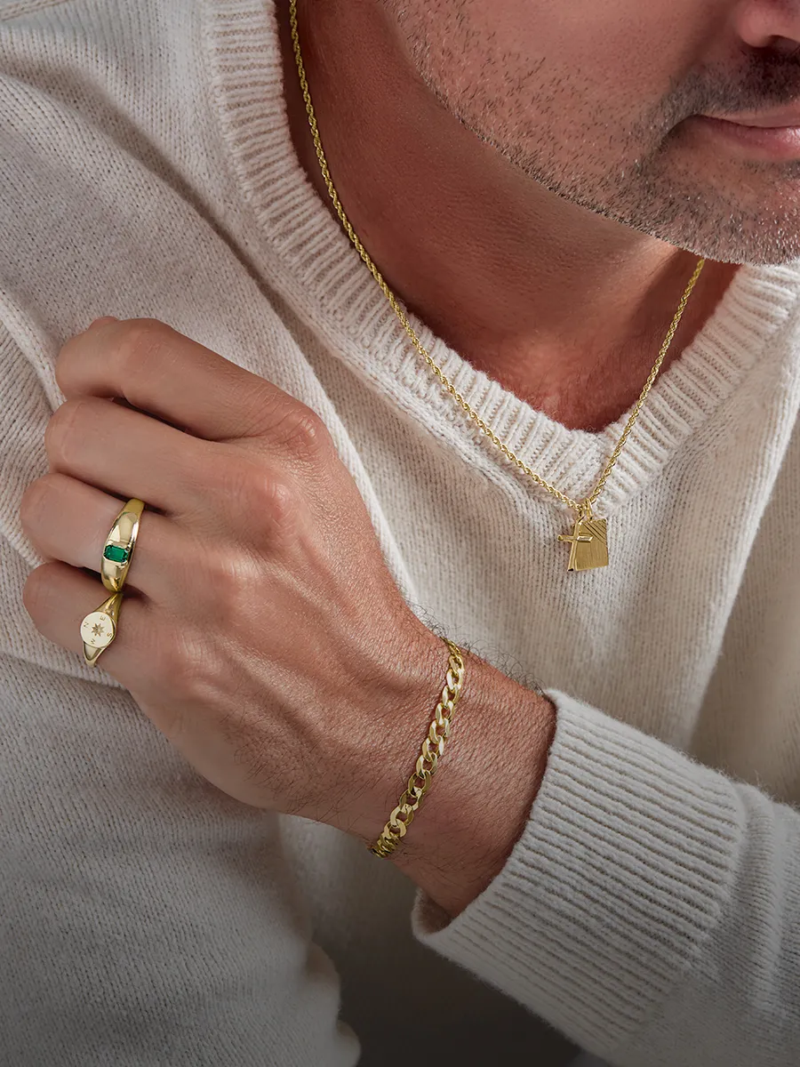 Man wearing gold necklace, bracelet, and rings with a white sweater.