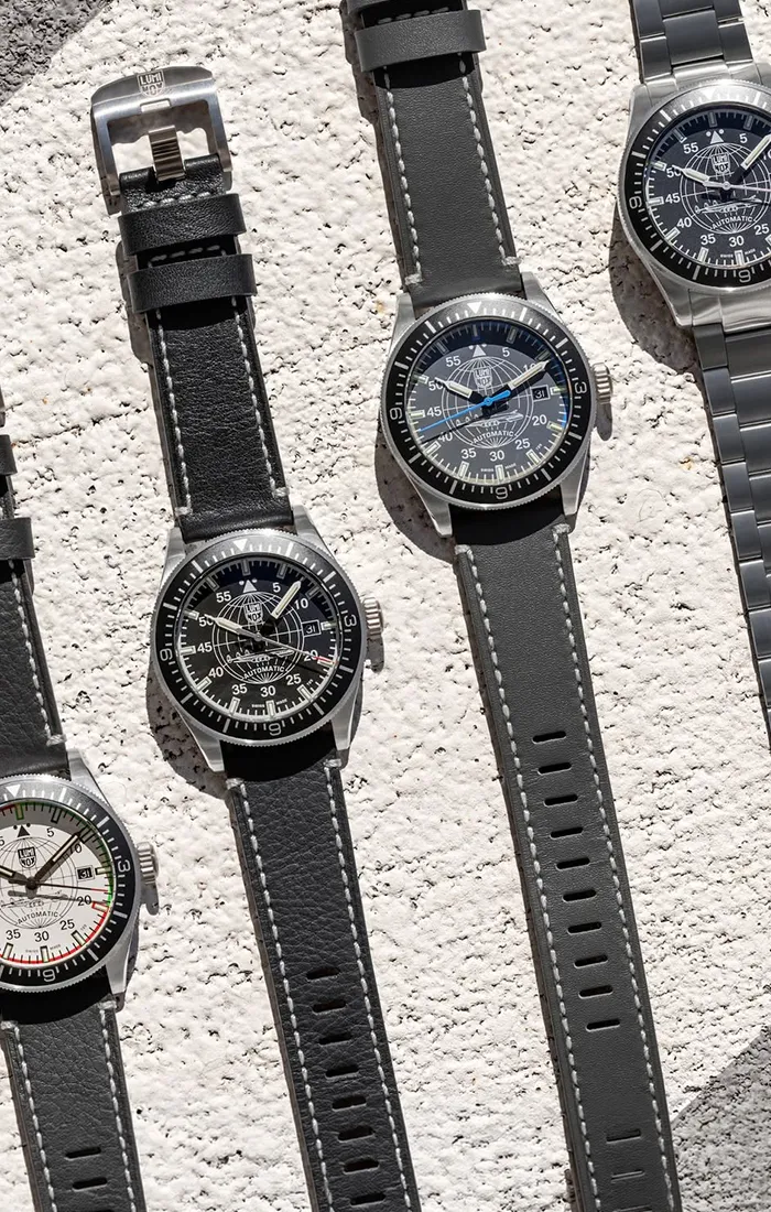 Four Luminox watches with black and gray straps displayed on a textured surface.