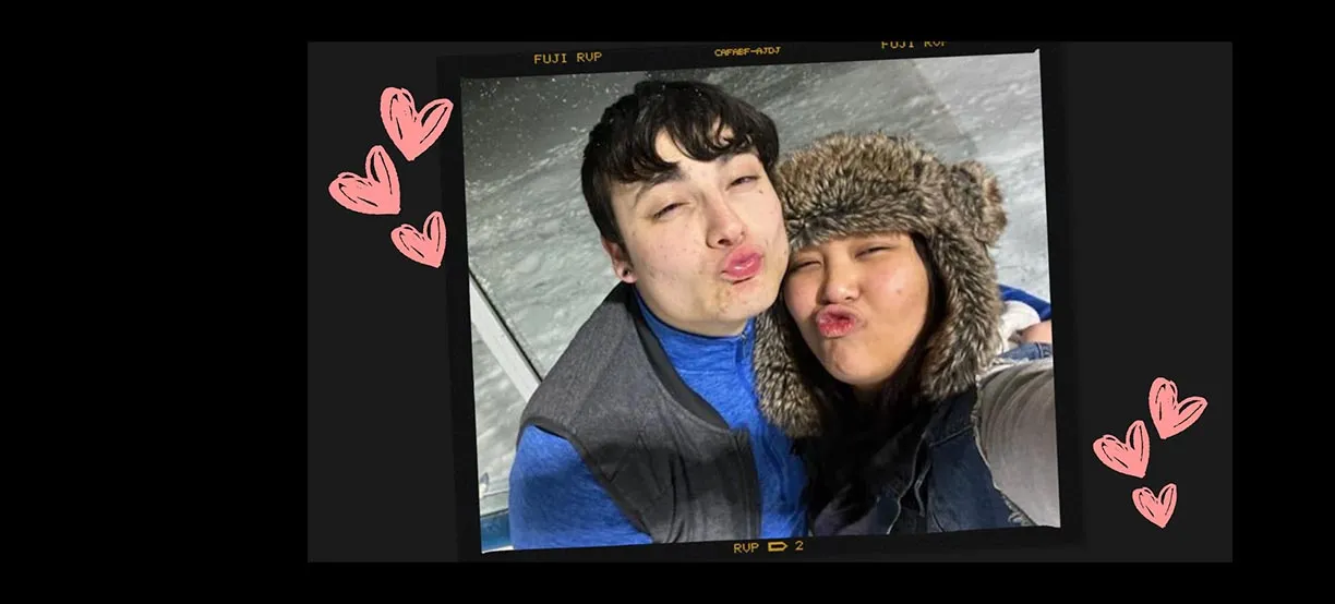 A couple making duck faces for a selfie, with pink heart doodles around the photo.