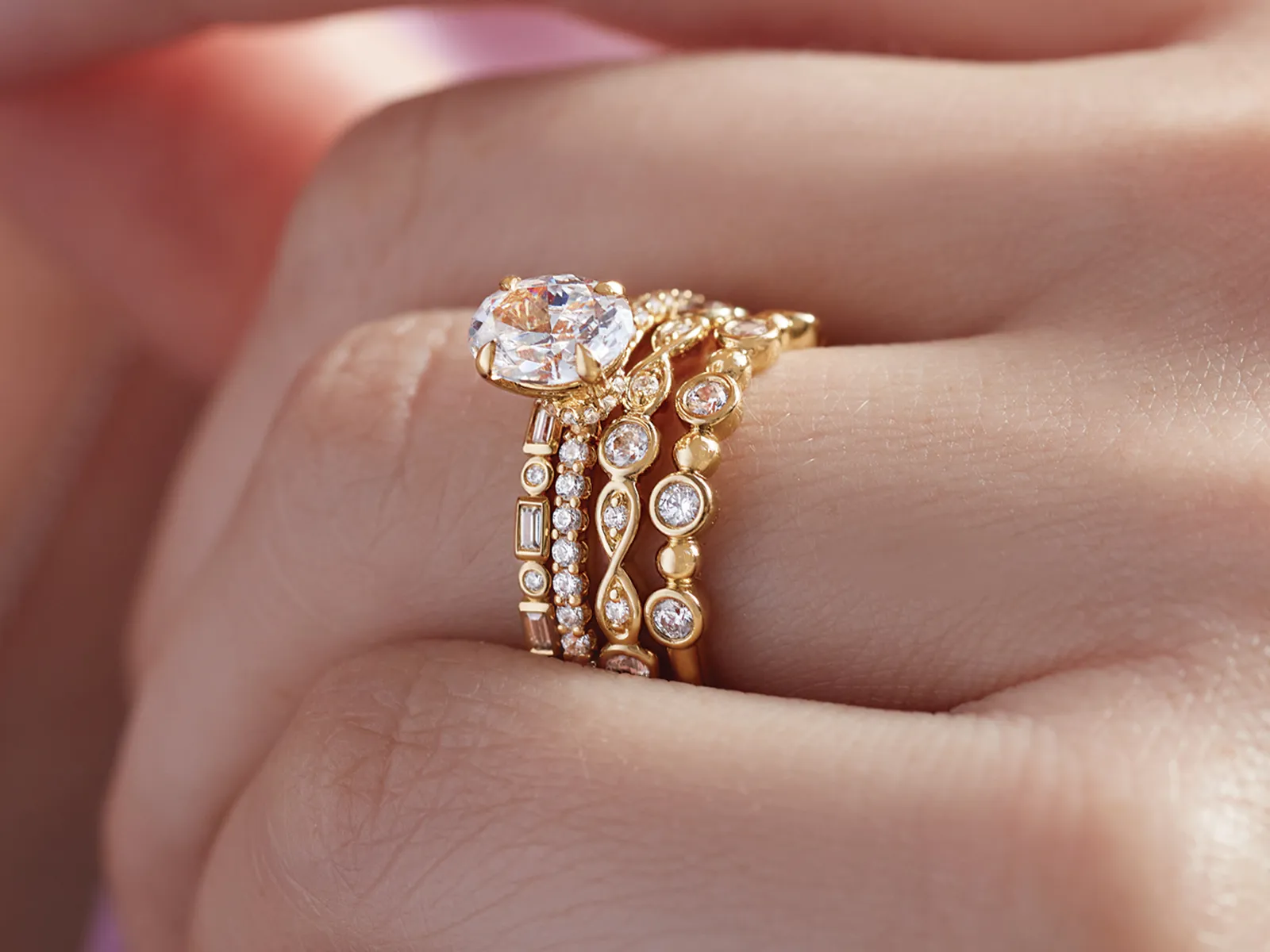 A hand holding a green and gray ring on a gold ring sizer, showcasing a unique design.