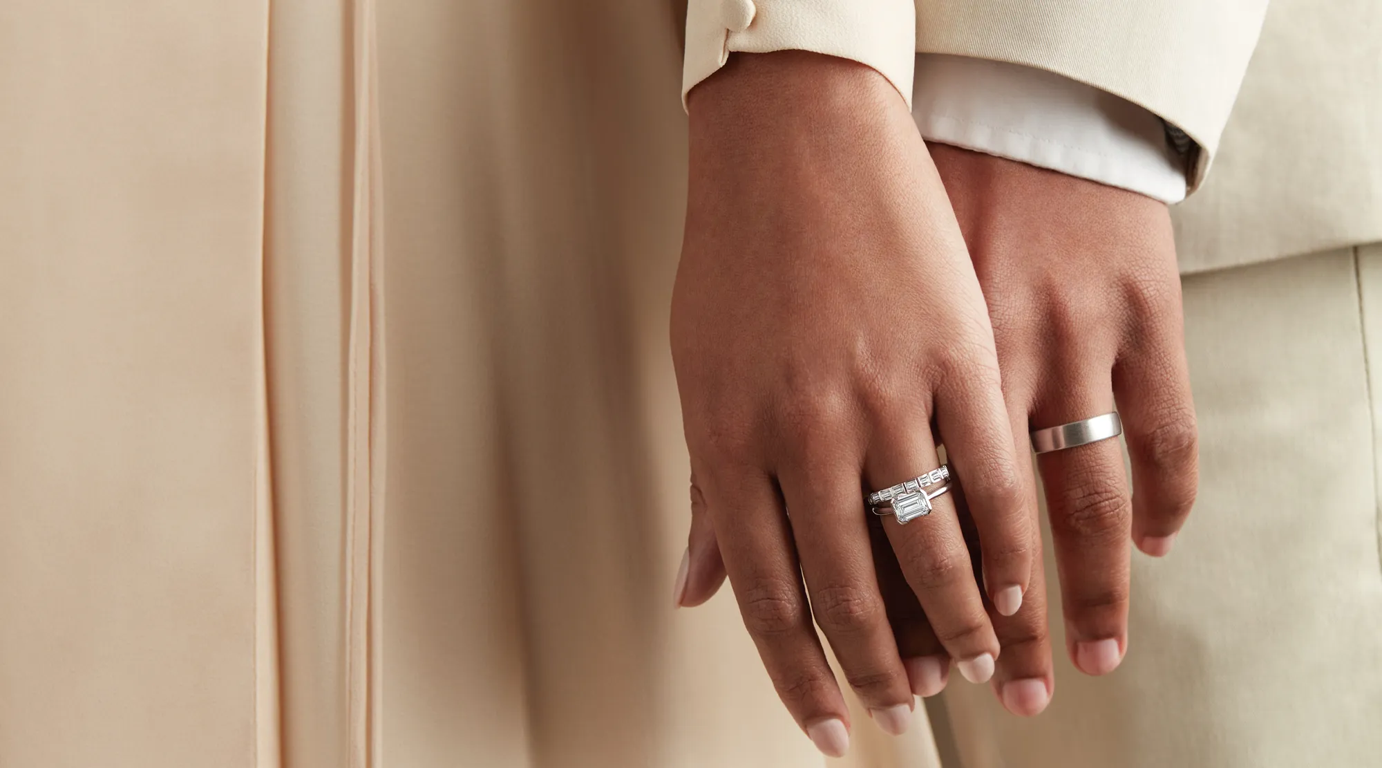 Couple holding hands, showcasing engagement and wedding rings.