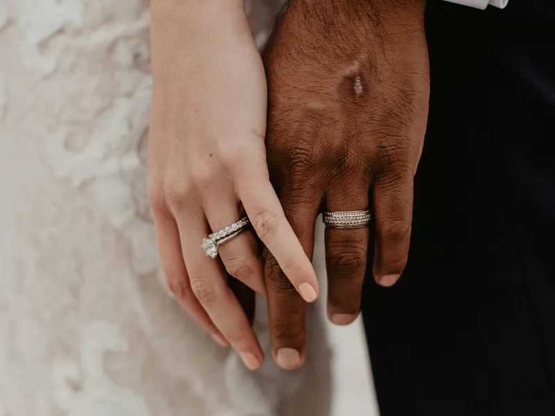 Close-up of a couple's hands showing wedding rings, symbolizing love and commitment.