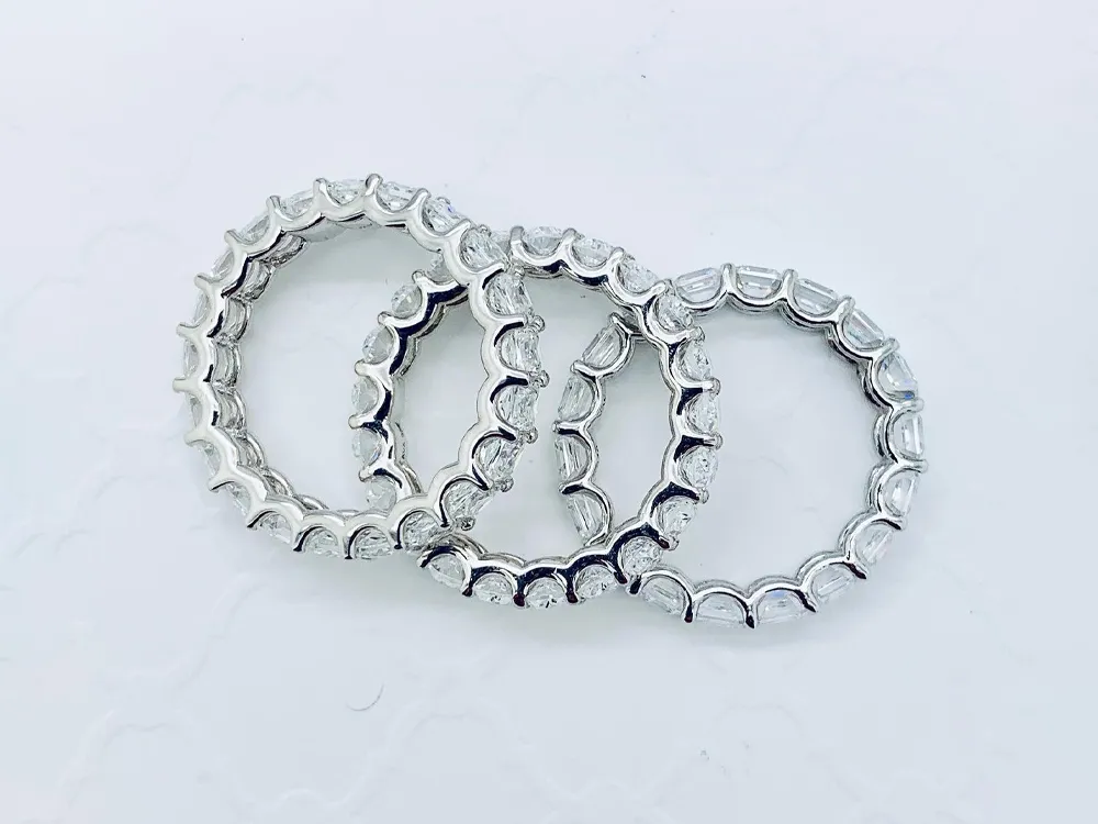 Three elegant silver wedding bands with sparkling accents, displayed together.