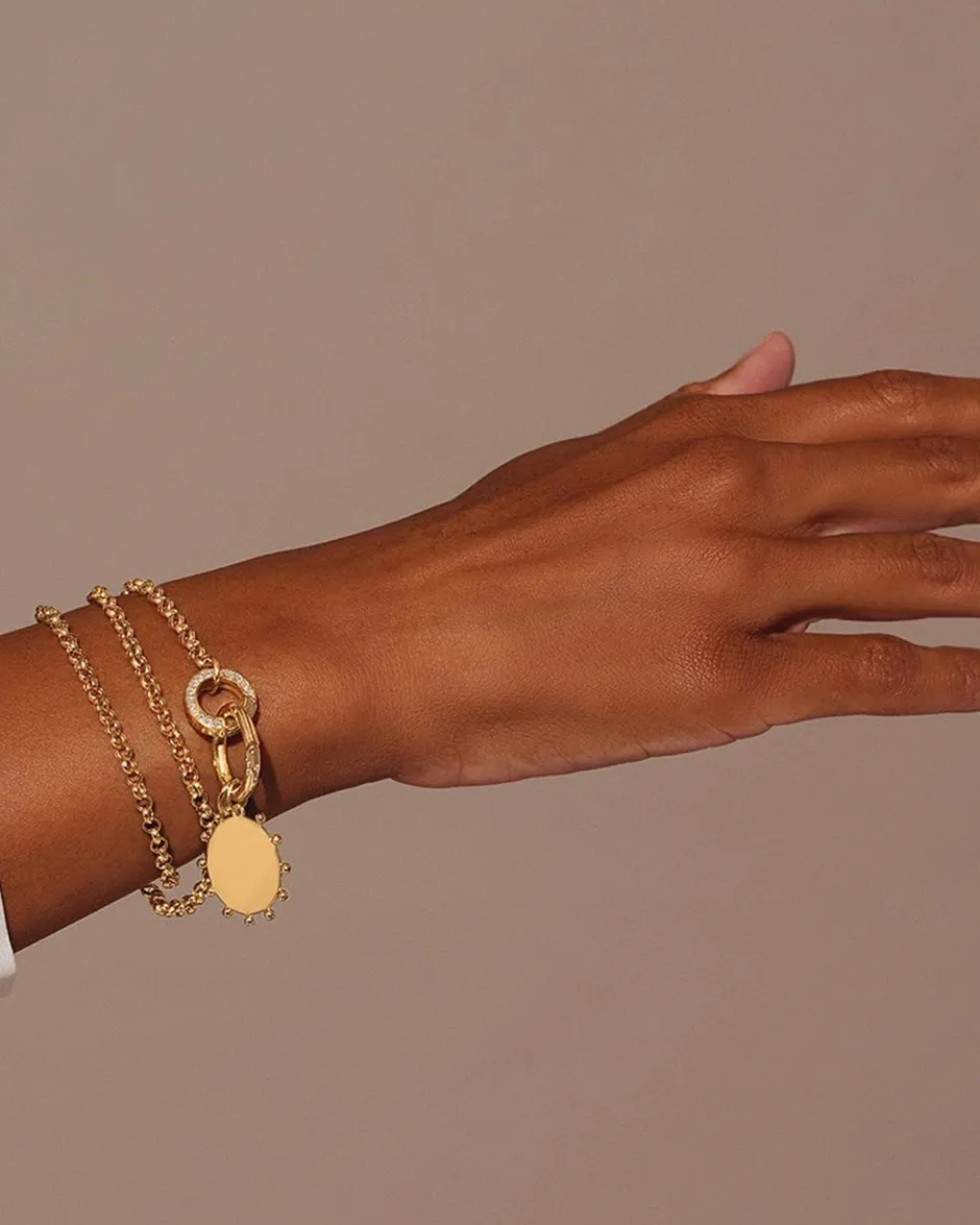 Gold bracelet with layered chains and a decorative charm on a model's wrist.