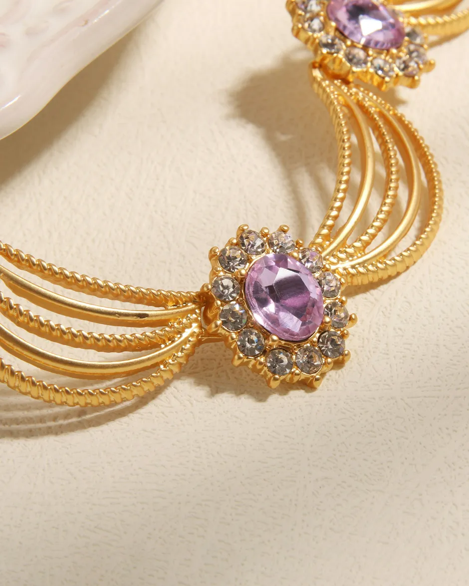 Gold necklace with purple and clear gemstones, showcasing elegant design.