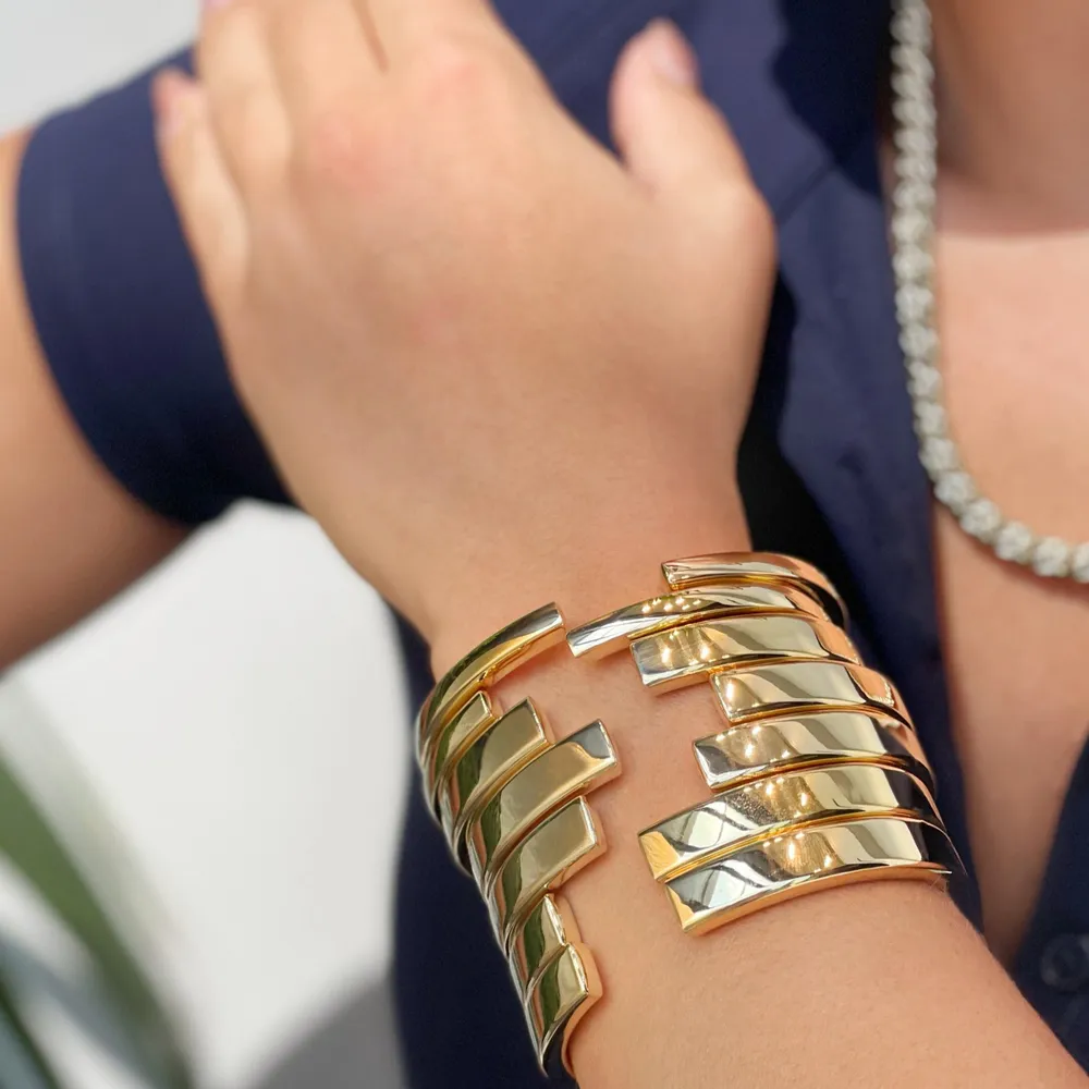 Gold cuff bracelet with sleek, modern design worn on a woman's wrist.