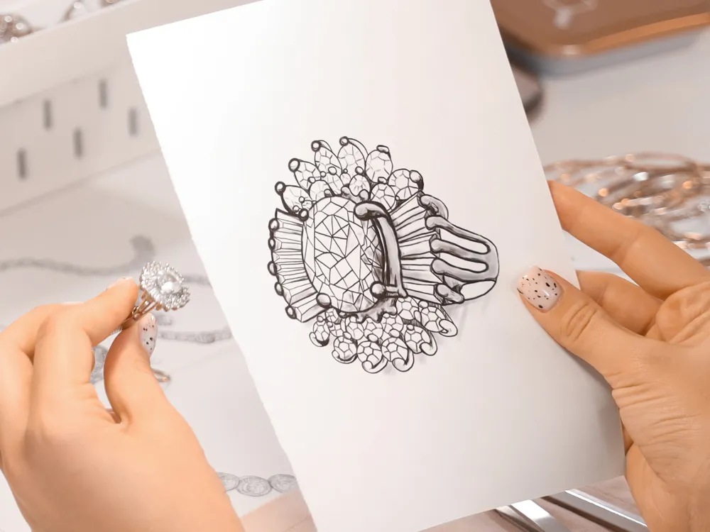 A person holds a ring next to a sketch of the same design, showcasing jewelry creativity.