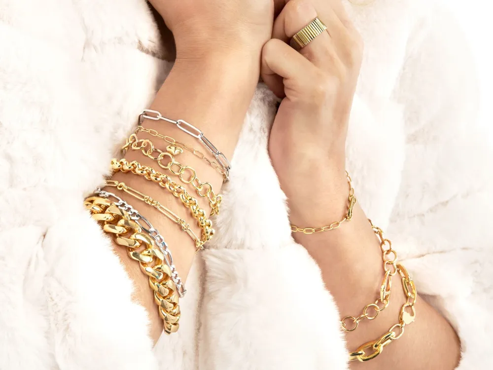 Close-up of multiple gold bracelets on a wrist, showcasing various styles and designs.
