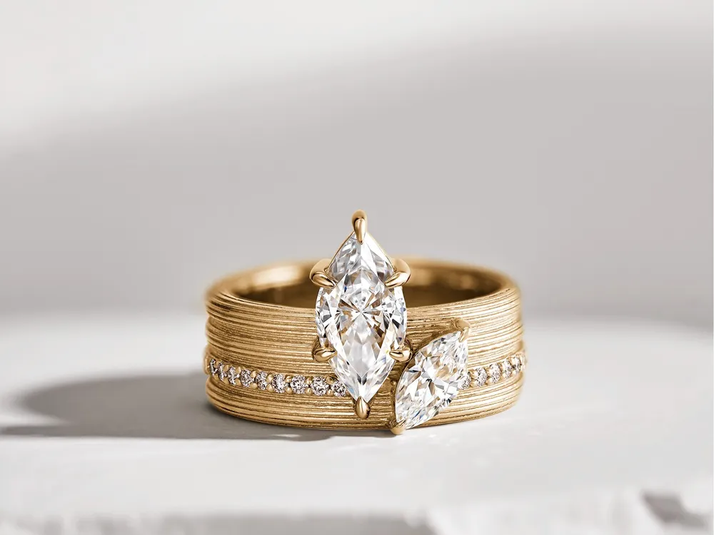 Elegant gold engagement ring featuring two marquise-cut diamonds and a band adorned with smaller diamonds.