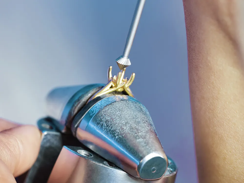 Jeweler working on a gold ring with a tool, showcasing craftsmanship.