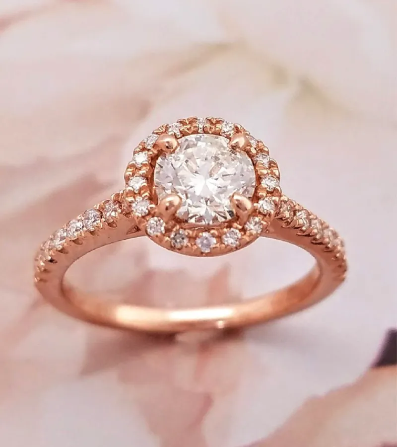 Rose gold engagement ring with a round diamond center and halo of smaller diamonds, available at Holly McHone Jewelers.