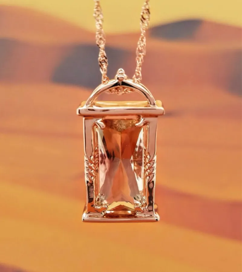 Gold  pendant necklace with a large gemstone, displayed against a desert background. Click here to shop gold jewelry 