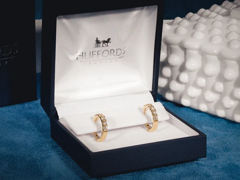 Elegant diamond drop earrings with various cuts on an ear.