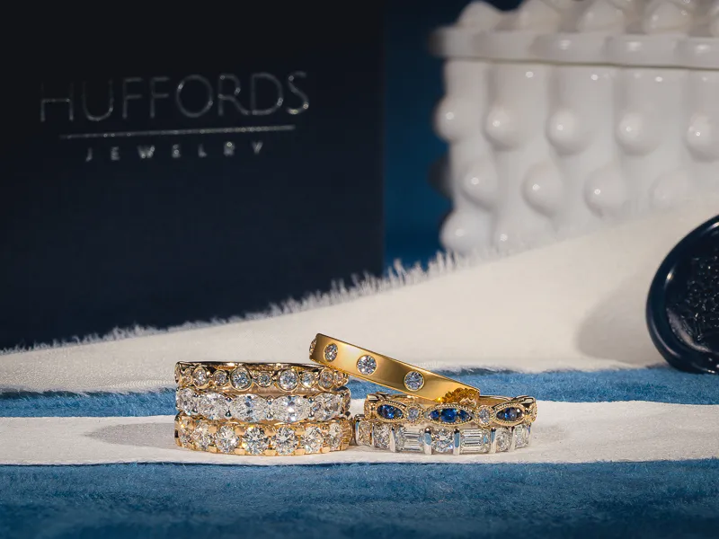 Sleek black wedding band with blue gemstones on a textured surface.