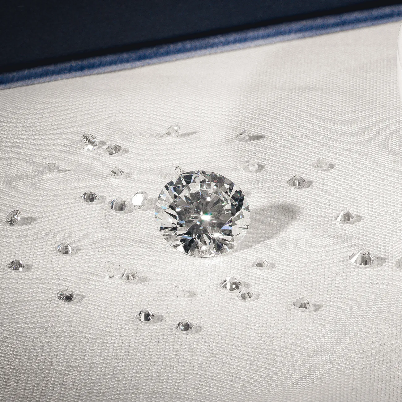 Sparkling round diamond surrounded by smaller diamonds on a white surface. Learn more about diamond education.