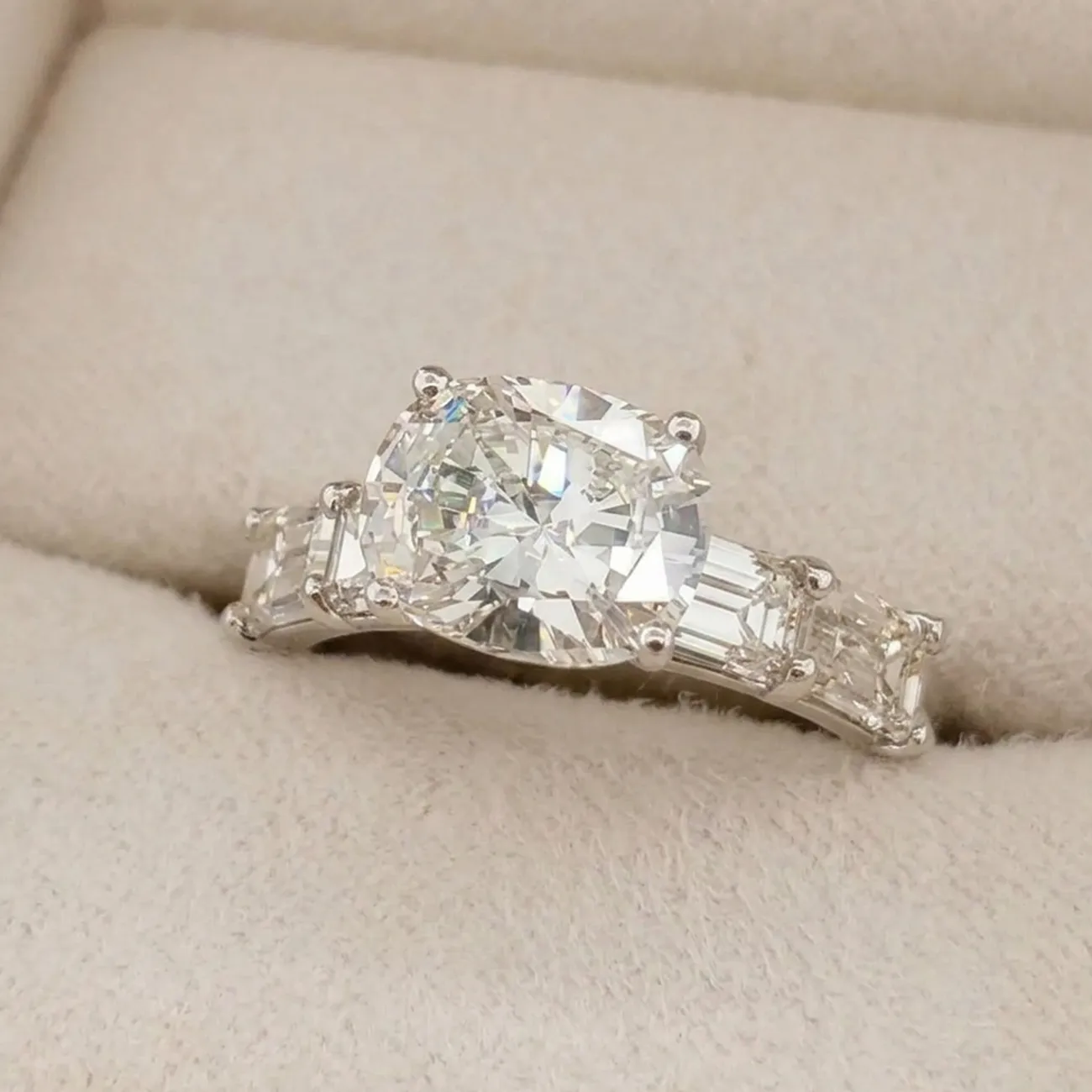 Radiant-cut diamond ring in a beige jewelry box.