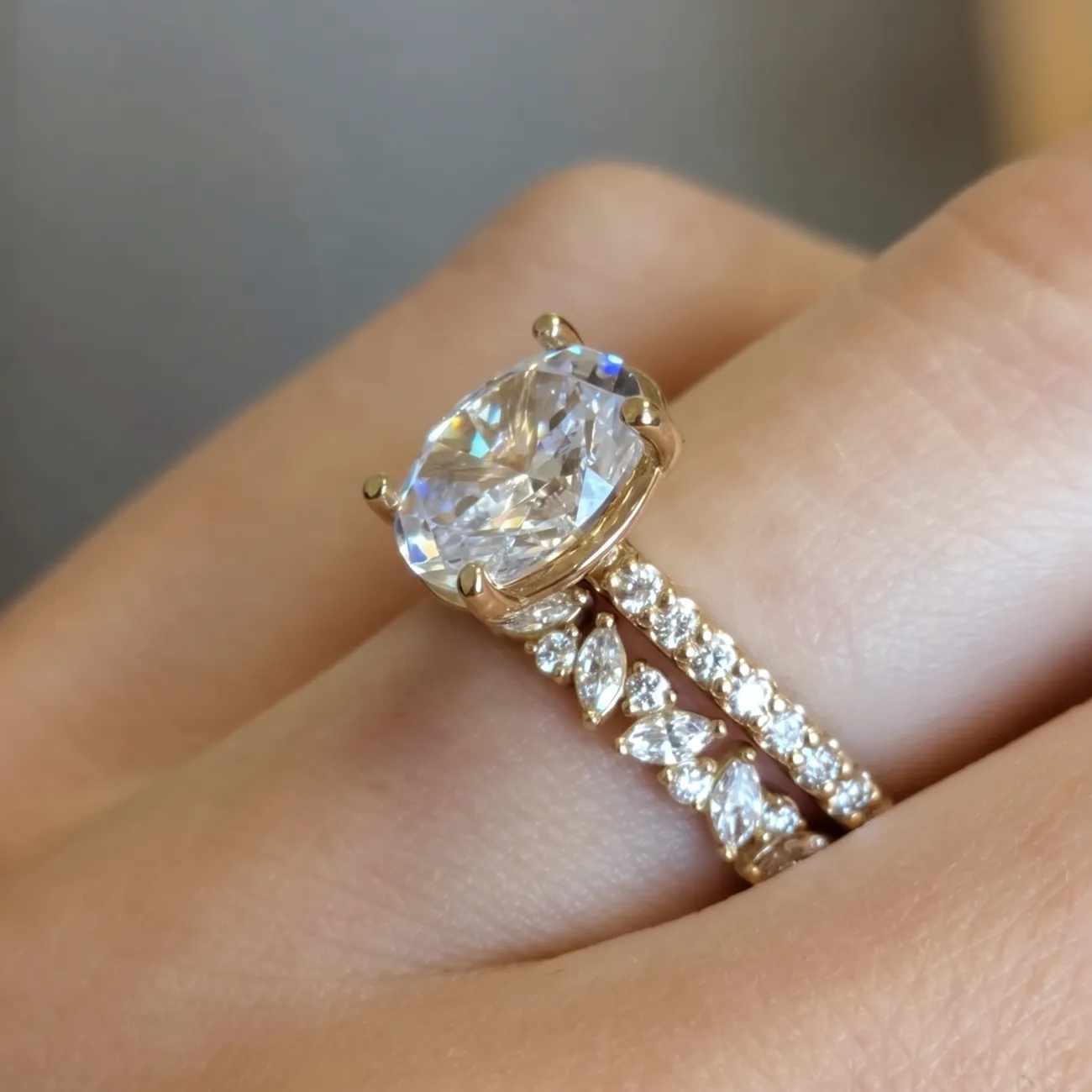 A hand wearing a large diamond ring with a matching diamond band.