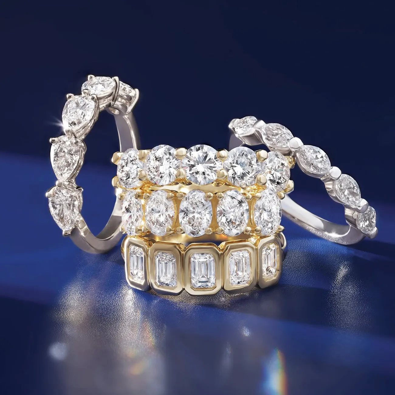 Three stacked diamond rings with various cuts on a dark background.