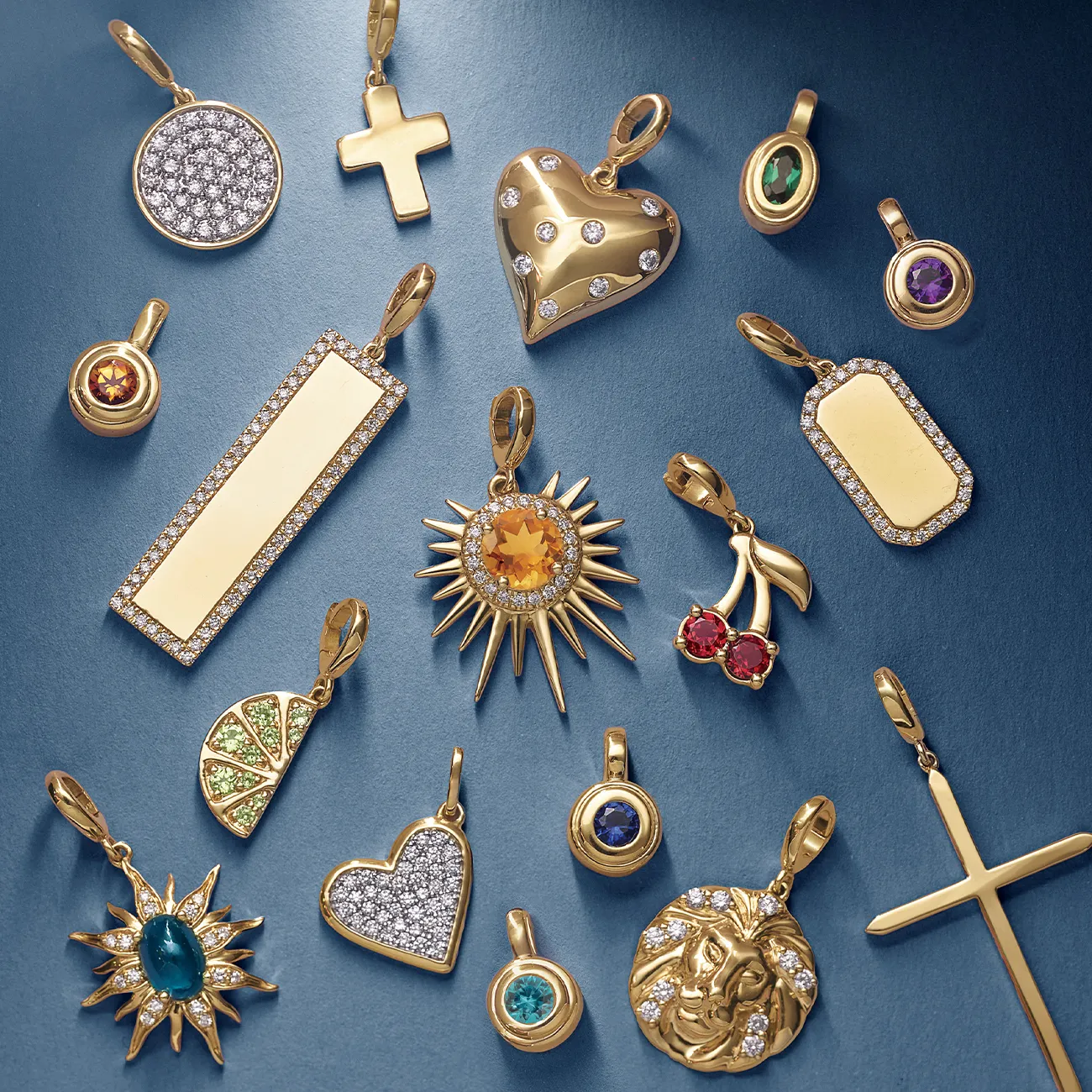 A collection of gold charms with various designs and gemstones on a blue background.