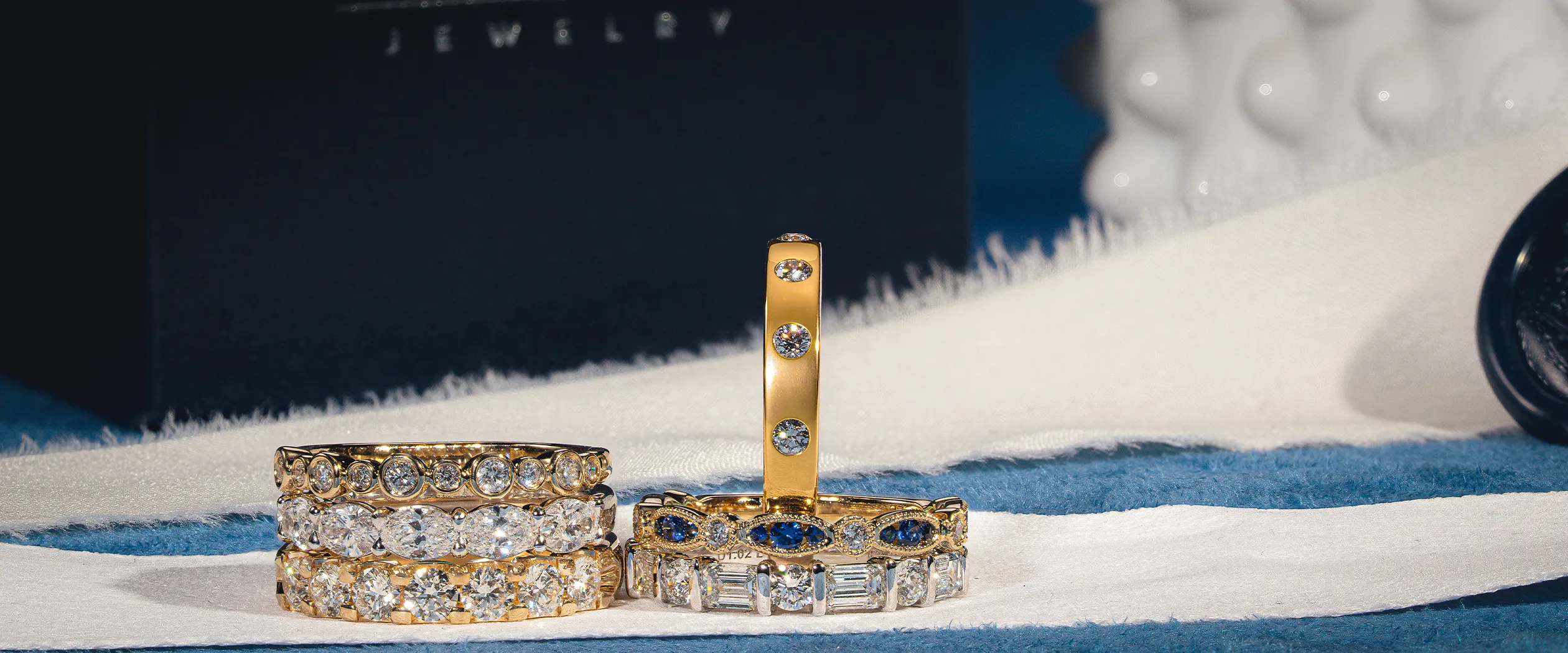 Elegant diamond and gemstone rings displayed on a white surface.