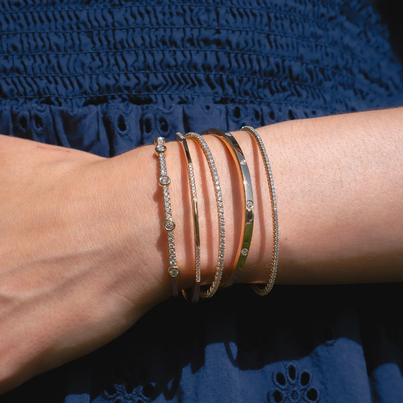 Elegant gold and diamond bracelets on a wrist, showcasing fine jewelry. Explore bracelets at Huffords Jewelry.