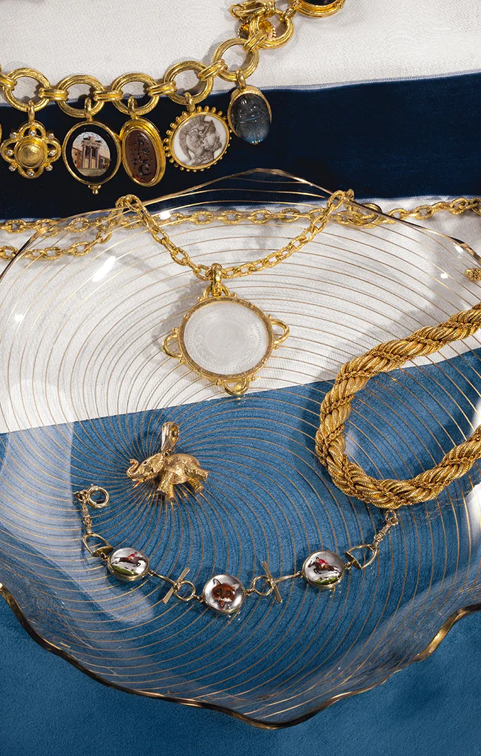 Elegant estate jewelry including rings, brooches, and a bracelet on a velvet and silk background.