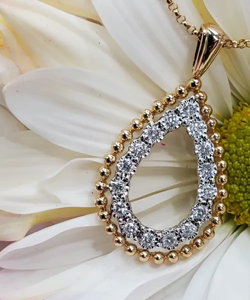 Gold teardrop pendant with diamonds on a flower background.