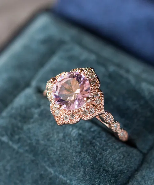 Elegant rose gold ring featuring a large pink gemstone surrounded by sparkling diamonds, displayed on a velvet cushion.