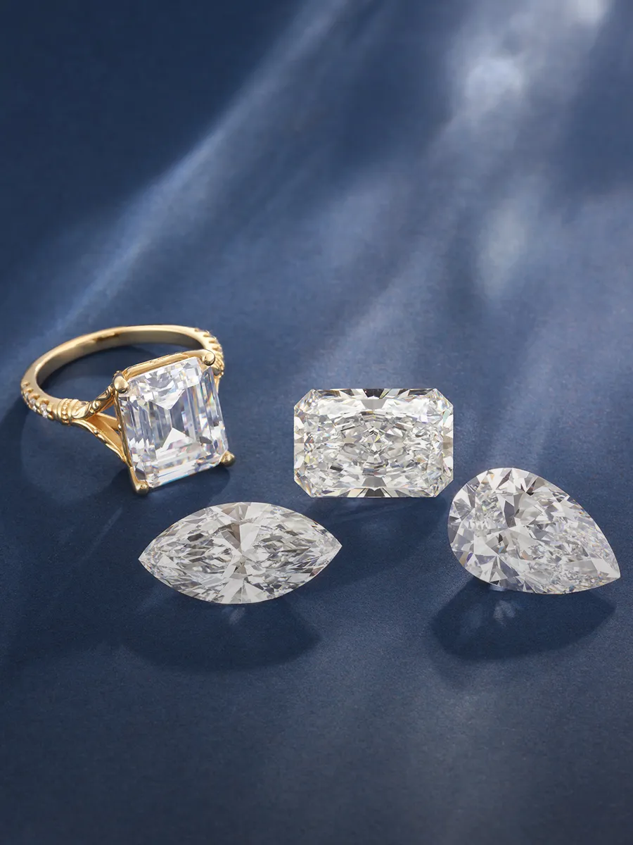 A gold ring with a large rectangular diamond and three loose diamonds on a blue background.