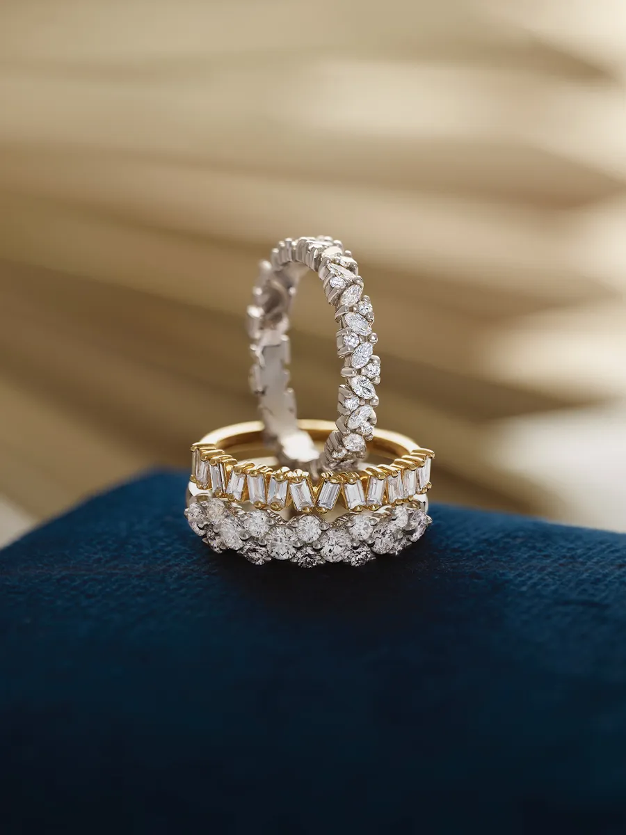 Three elegant diamond wedding bands stacked on a blue velvet surface.