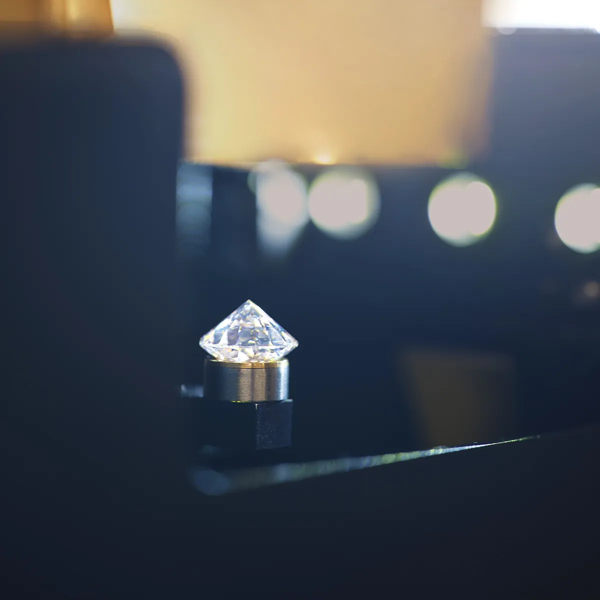 A diamond on a metal holder with blurred lights in the background.