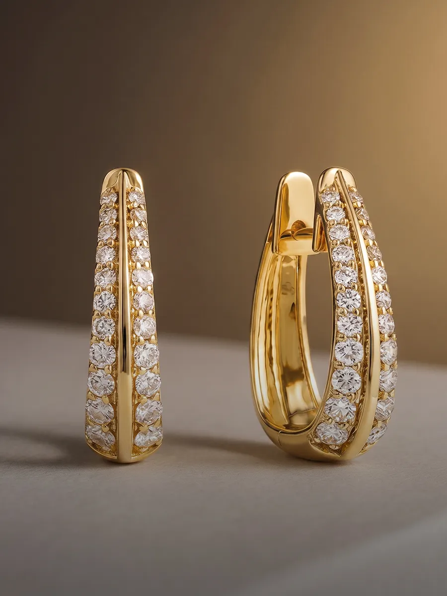 Gold hoop earrings with rows of sparkling diamonds on a neutral background.