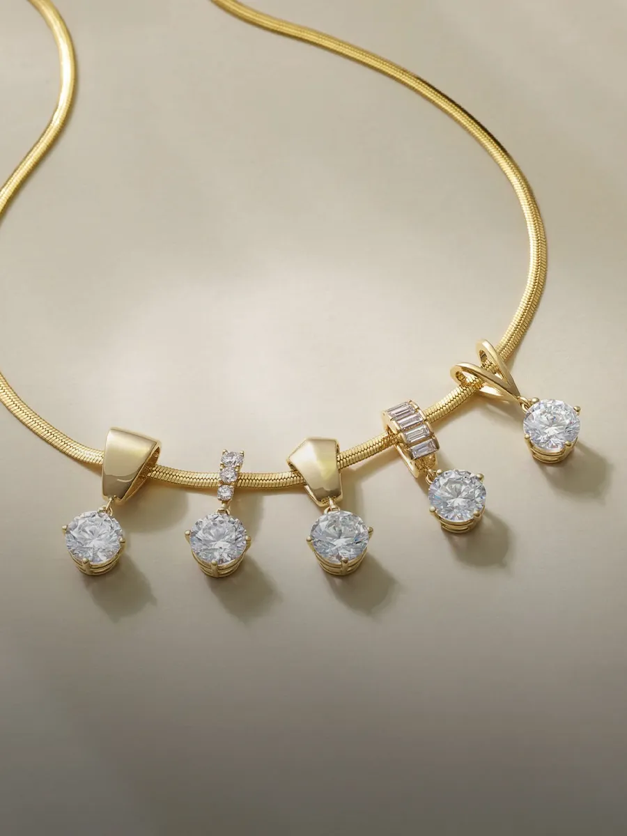 Gold necklace with five diamond pendants on a light background.