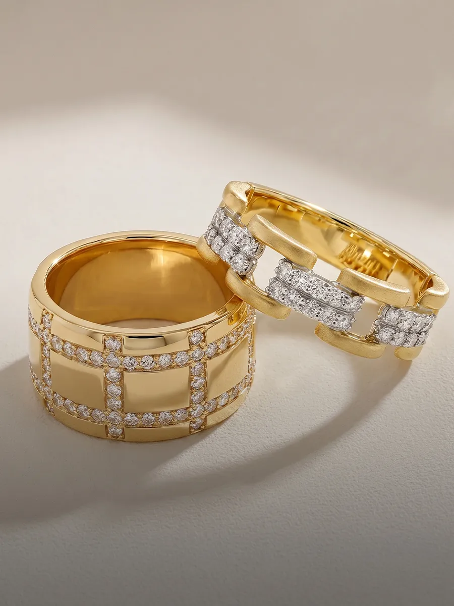 Two gold rings with diamond accents on a light background.