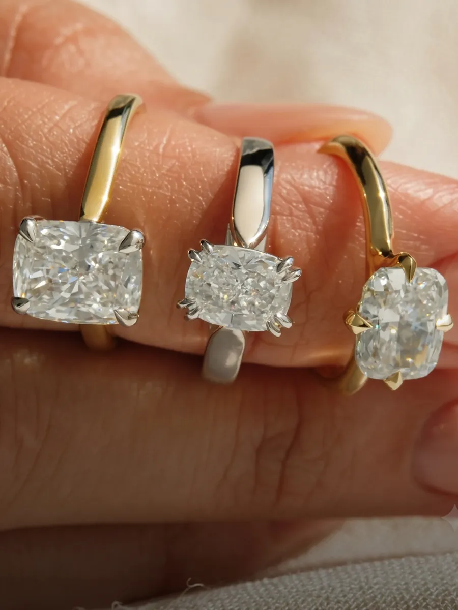 Three diamond engagement rings with gold and silver bands displayed on fingers.