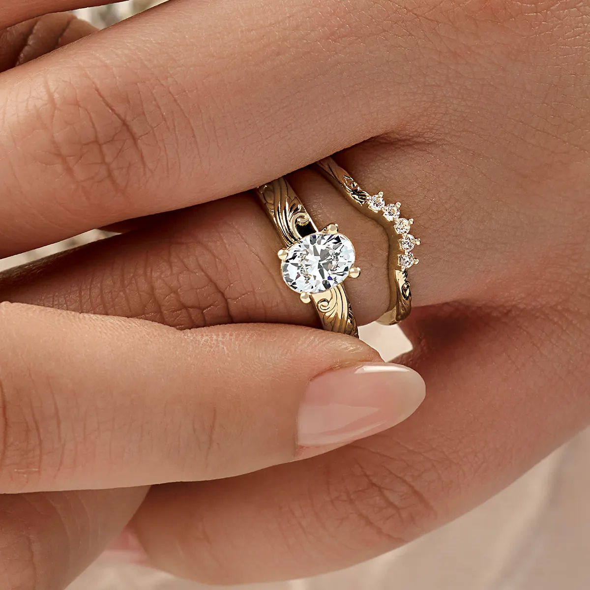 Two gold rings on a finger, one with a large diamond and the other with smaller diamonds.