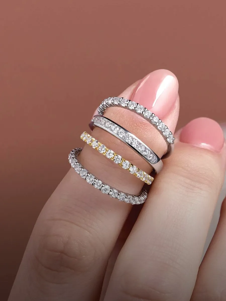 Three diamond-studded rings on fingers with pink nails against a brown background.