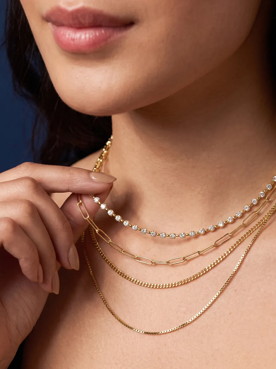 A woman wearing layered gold and diamond necklaces, close-up view.