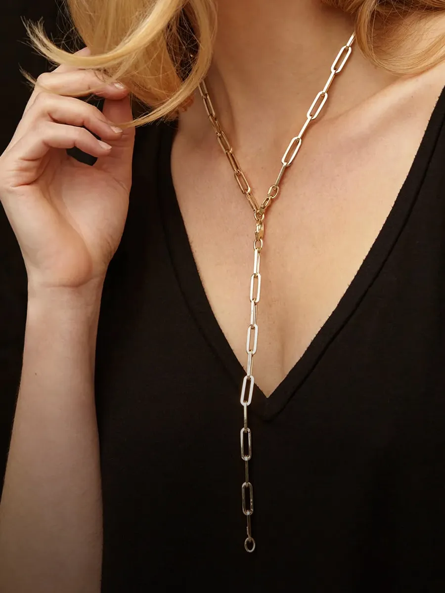 A woman wearing a gold chain necklace with a V-neck black top.