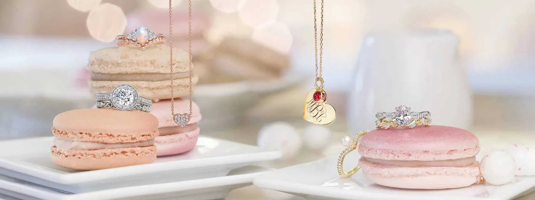 Jewelry displayed on macarons, featuring rings and necklaces on white plates with a soft, blurred background.