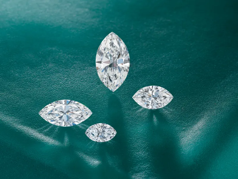 Four marquise-cut diamonds on a textured teal background.