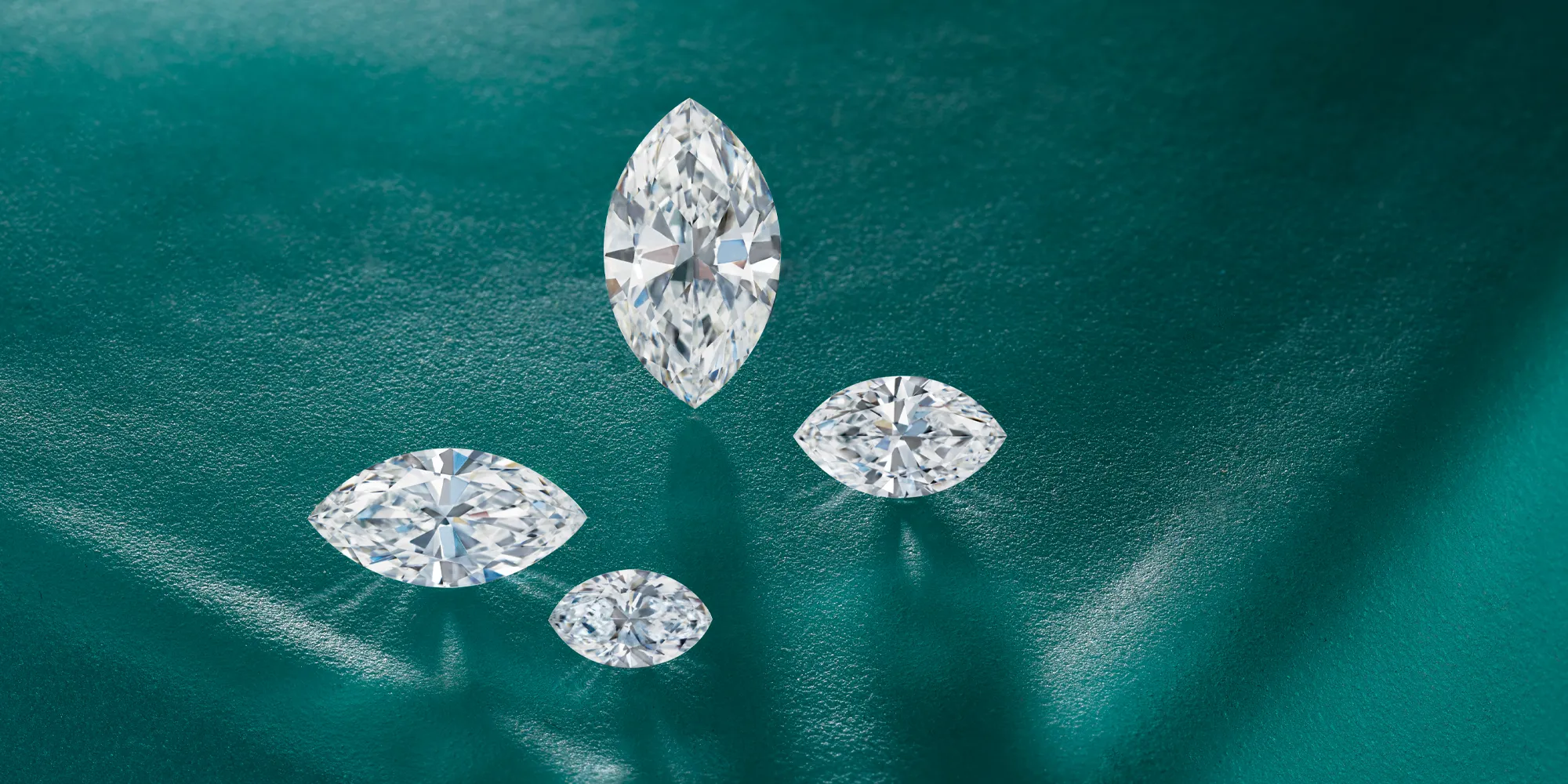 Four marquise-cut diamonds on a textured teal background.