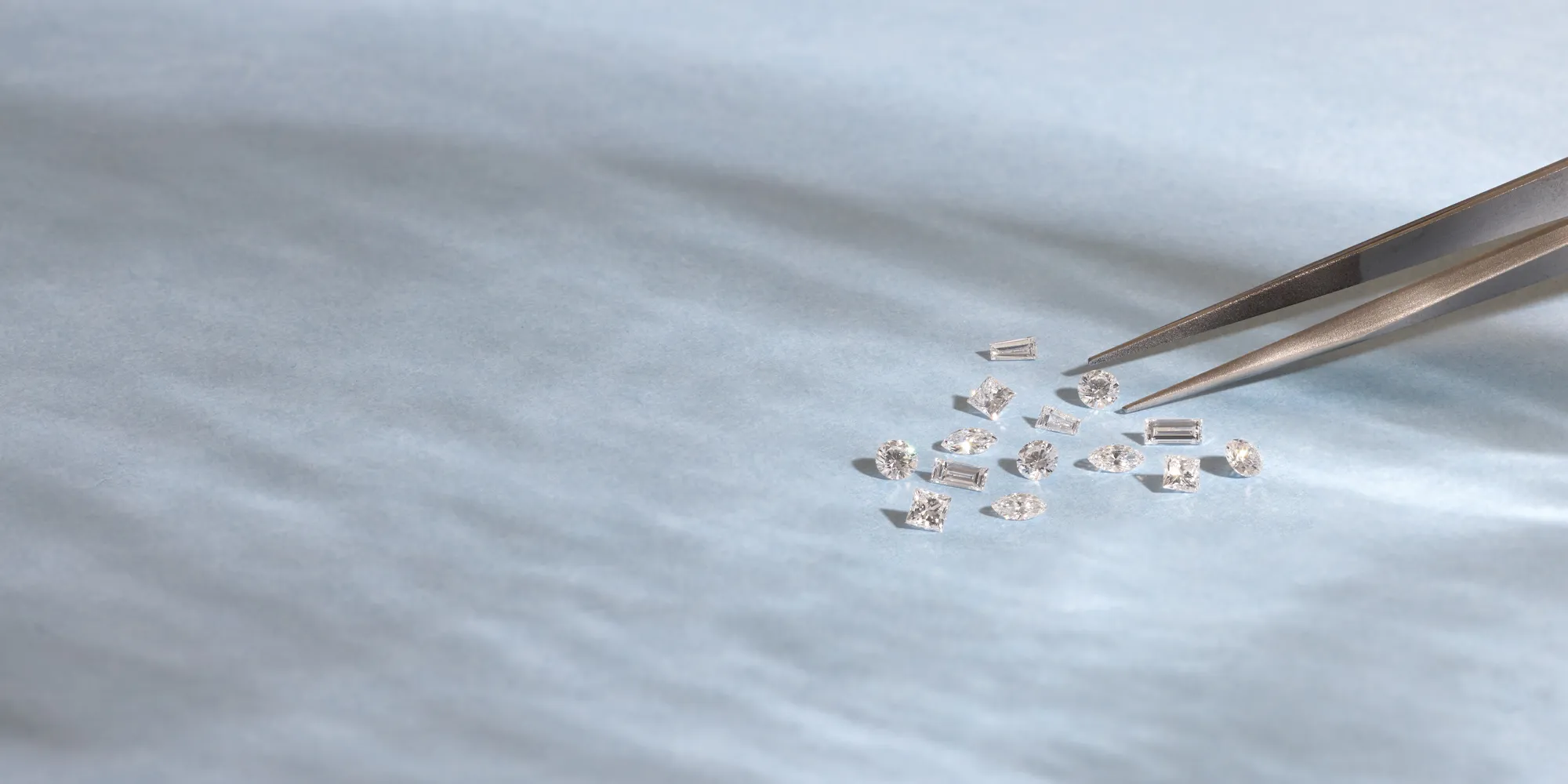 Diamonds on paper with tweezers. Click to contact JA Diamonds for expert support.
