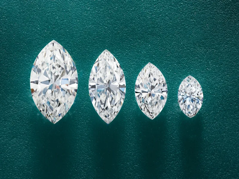 Four marquise-cut diamonds of varying sizes on a textured green background.