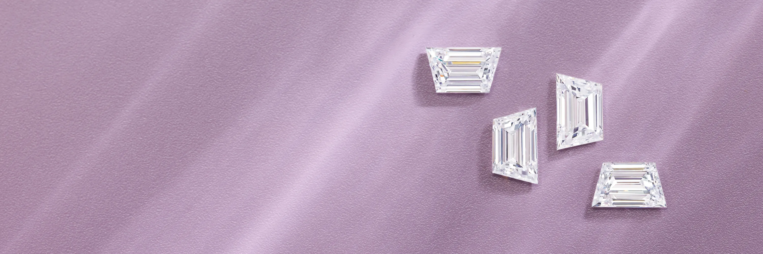 Three emerald-cut diamonds on a textured lavender background.