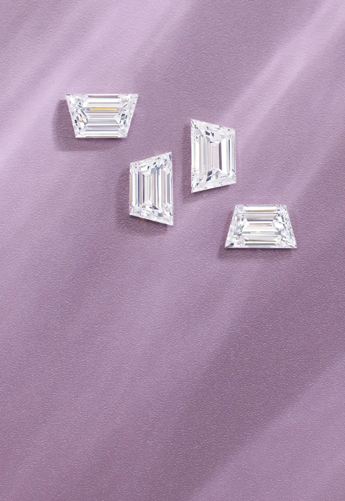 Three emerald-cut diamonds on a textured lavender background.
