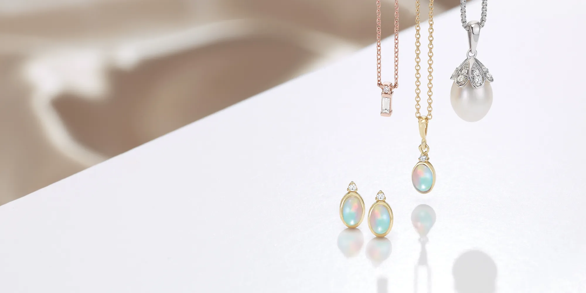 Elegant necklaces and earrings with opal and pearl accents on a reflective surface.