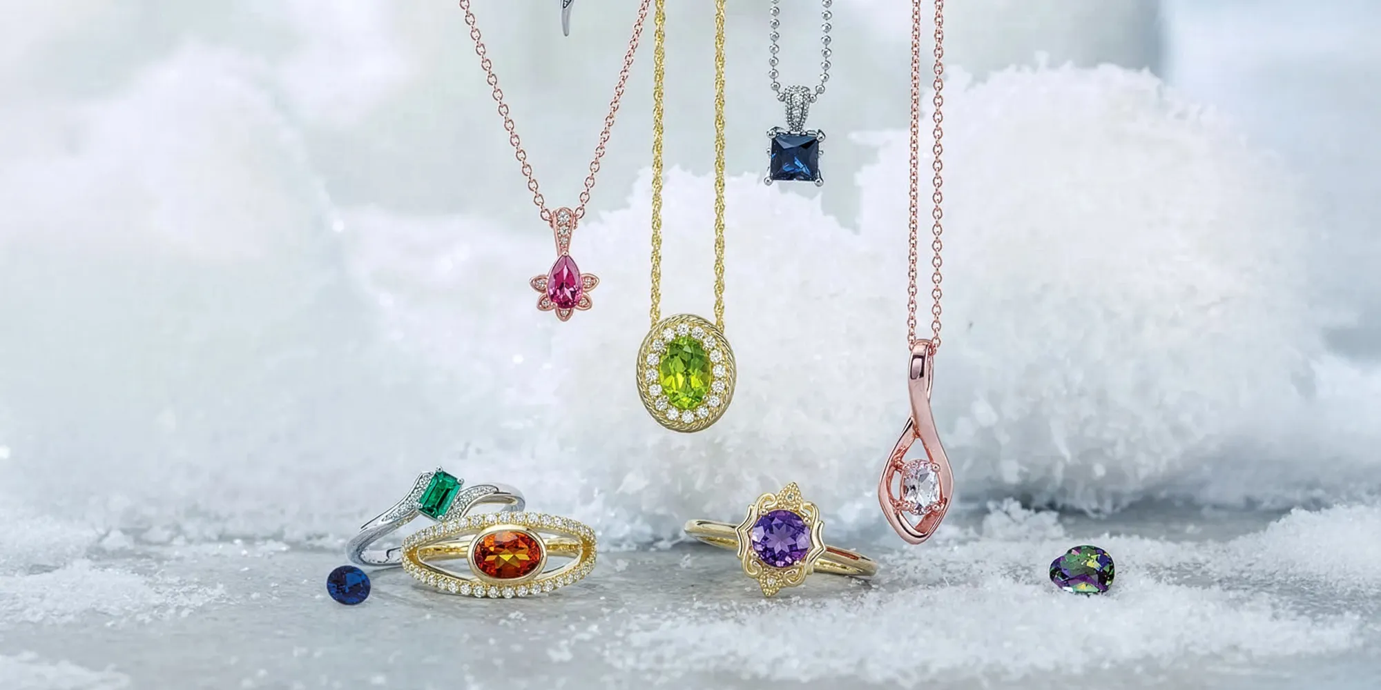 Colorful gemstone necklaces and rings displayed on a snowy surface.