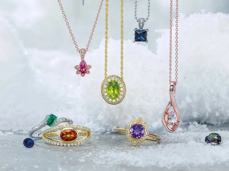 Colorful gemstone necklaces and rings displayed on a snowy surface.