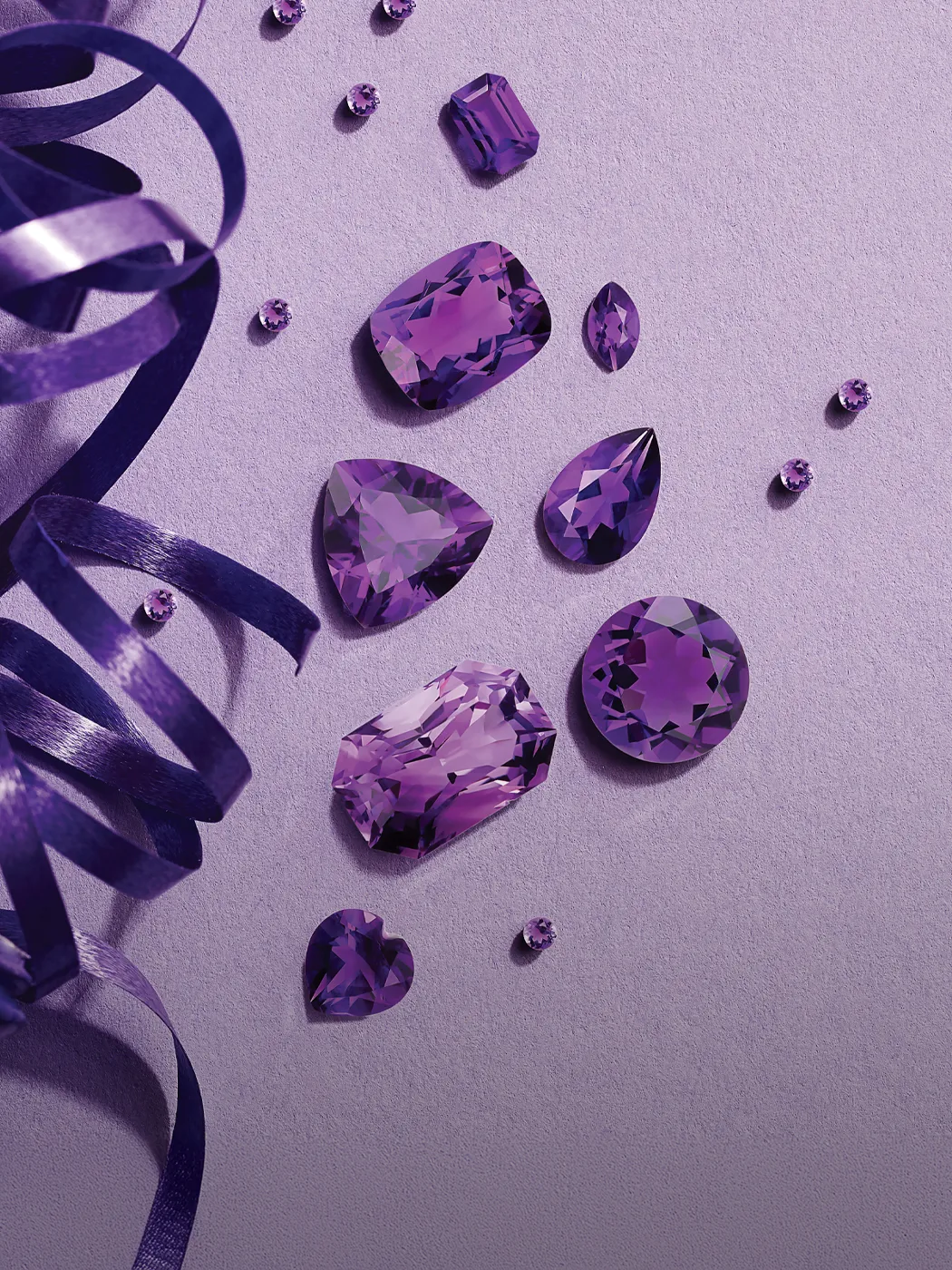 Purple gemstones and ribbon on a lavender background.